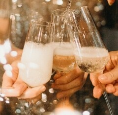 3 champagne glasses being held together and filled with champagne at a party